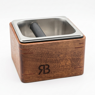 Wooden espresso knock box with metal inset on a white background