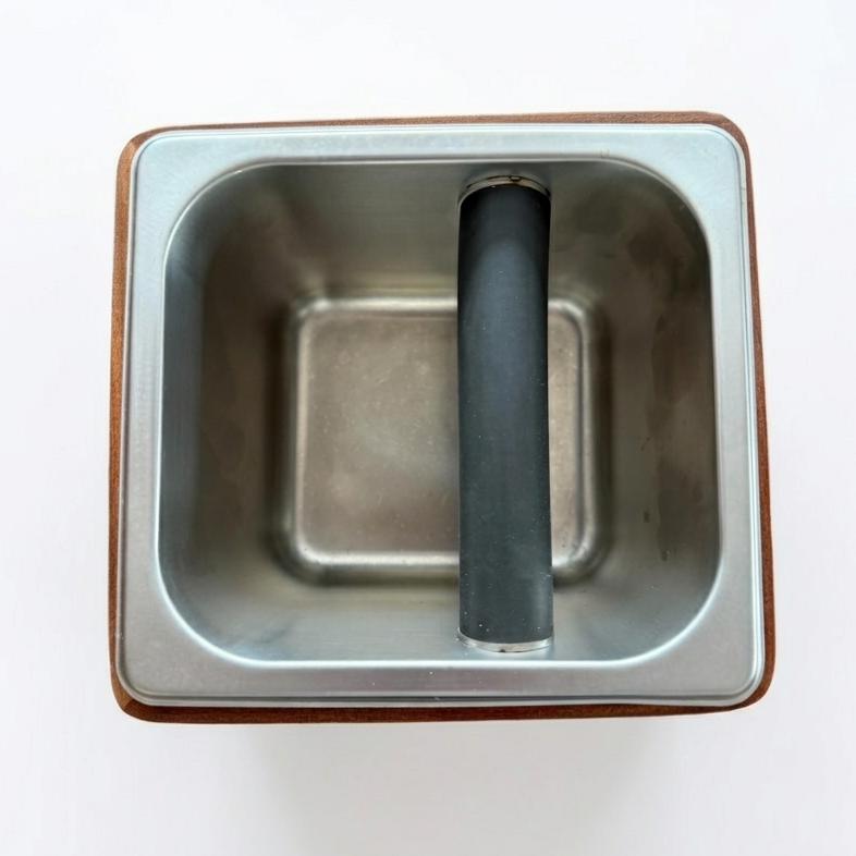 Wooden espresso knock box with metal inset on a white background