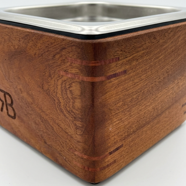 Wooden espresso knock box with metal inset on a white background